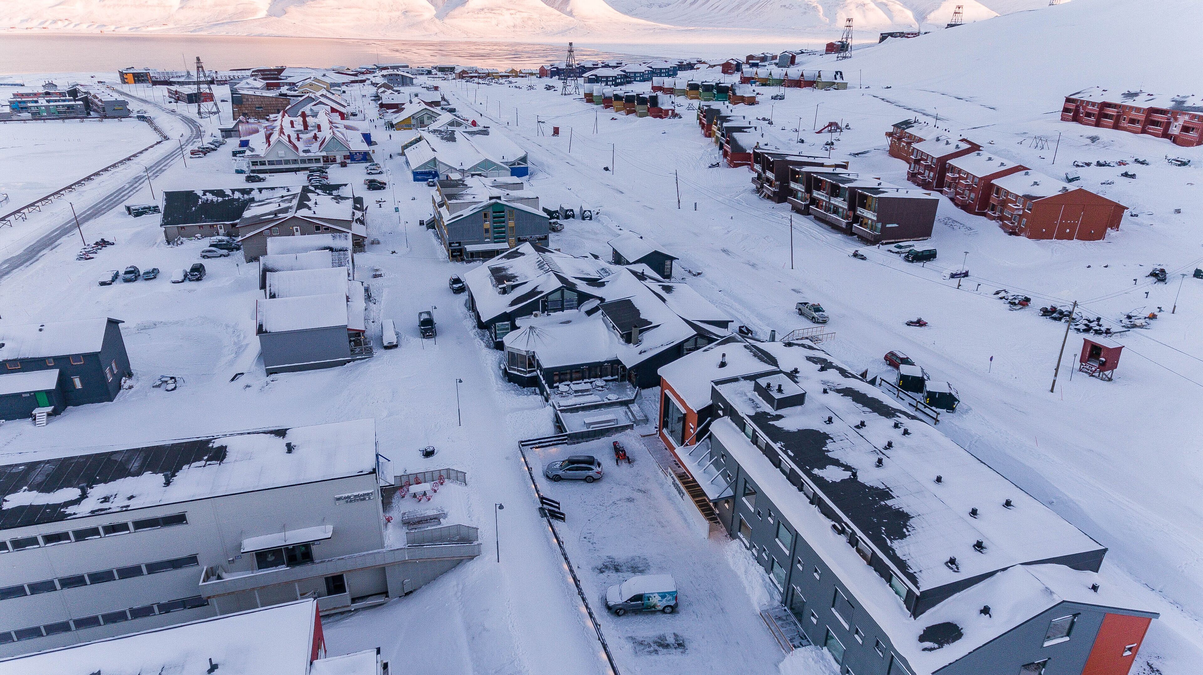 A snow-covered town with buildings, roads, and vehicles.