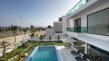 A modern building with a rooftop pool, outdoor seating, and a view of the coastline.