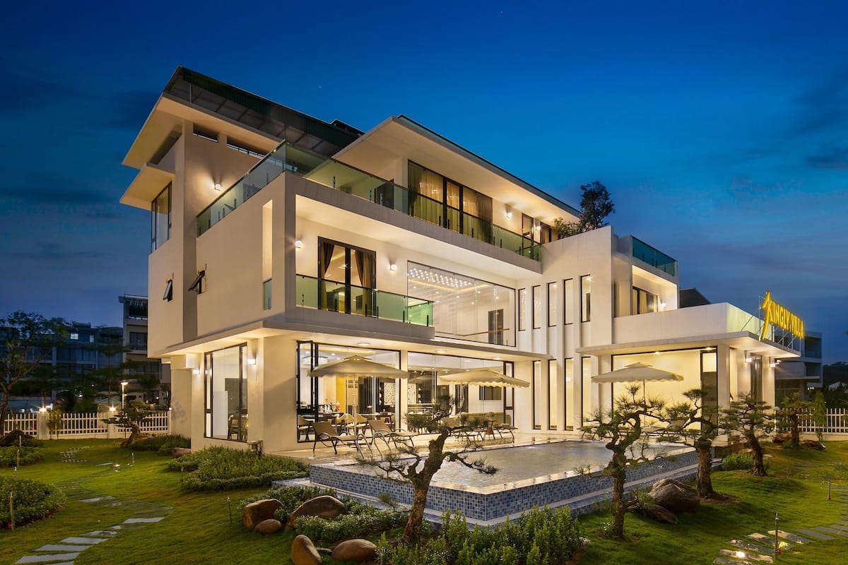 A modern two-story house with a pool, outdoor seating, and a well-maintained garden.