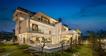 A modern two-story house with a pool, outdoor seating, and a well-maintained garden.
