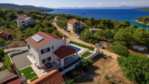 A modern two-story house with a swimming pool, surrounded by lush greenery and a view of the sea. - Villa Makarac (Milna)