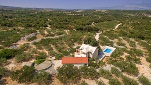 An aerial view of a property with a red-roofed building, a swimming pool, and surrounding greenery. - Villa Dubrava (Pucisca)