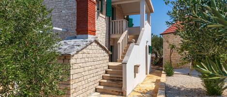 A stone house with a stone staircase leading to a balcony.