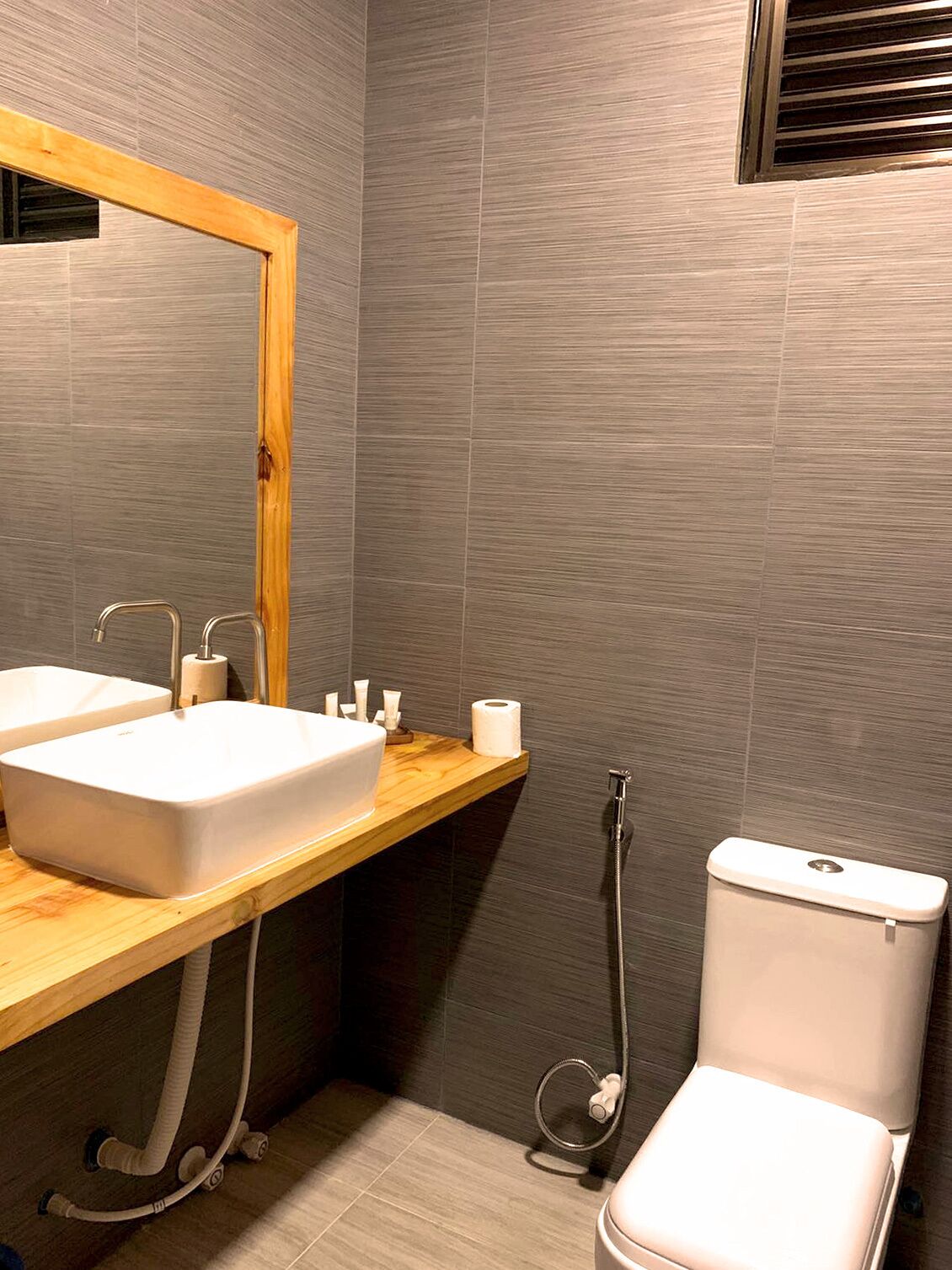 A modern bathroom with two sinks, a toilet, and a shower.