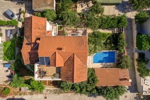 An aerial view of a property with a swimming pool, multiple buildings with red-tiled roofs, and surrounding greenery. - Villa Lukrecia (Supetar)