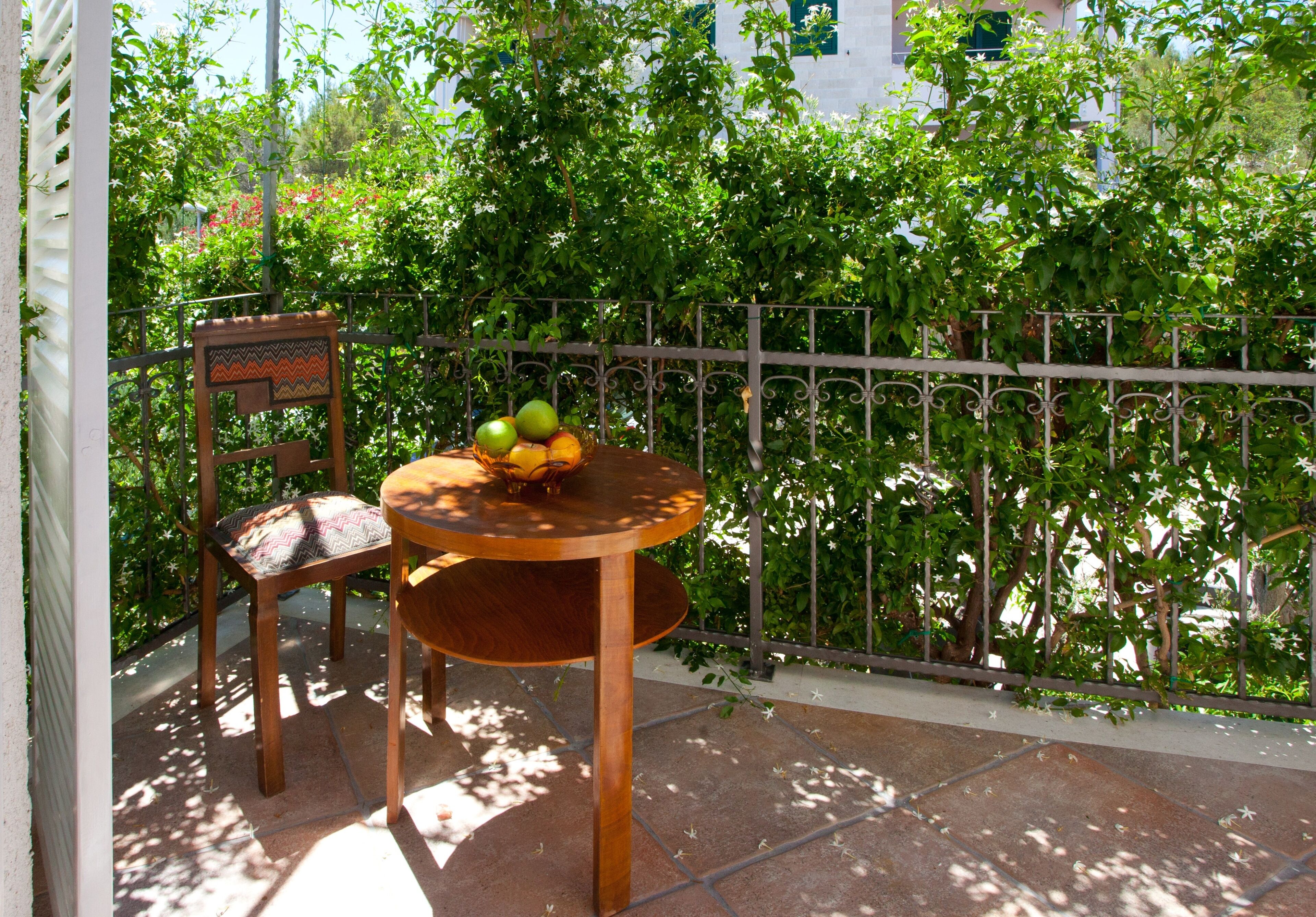 Una silla y una mesa de madera con un frutero en un balcón.