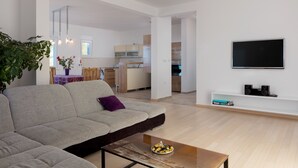 Un saló modern amb un sofà, una taula de centre i un televisor muntat a la paret.