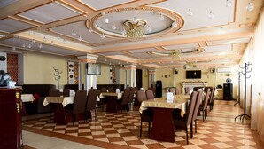 A dining area with checkered flooring, multiple tables, and chairs. - Alatau Hotel (Astana)