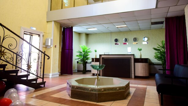 Eine Lobby mit Empfangsschalter, Treppe, Brunnen und einer Sitzecke.