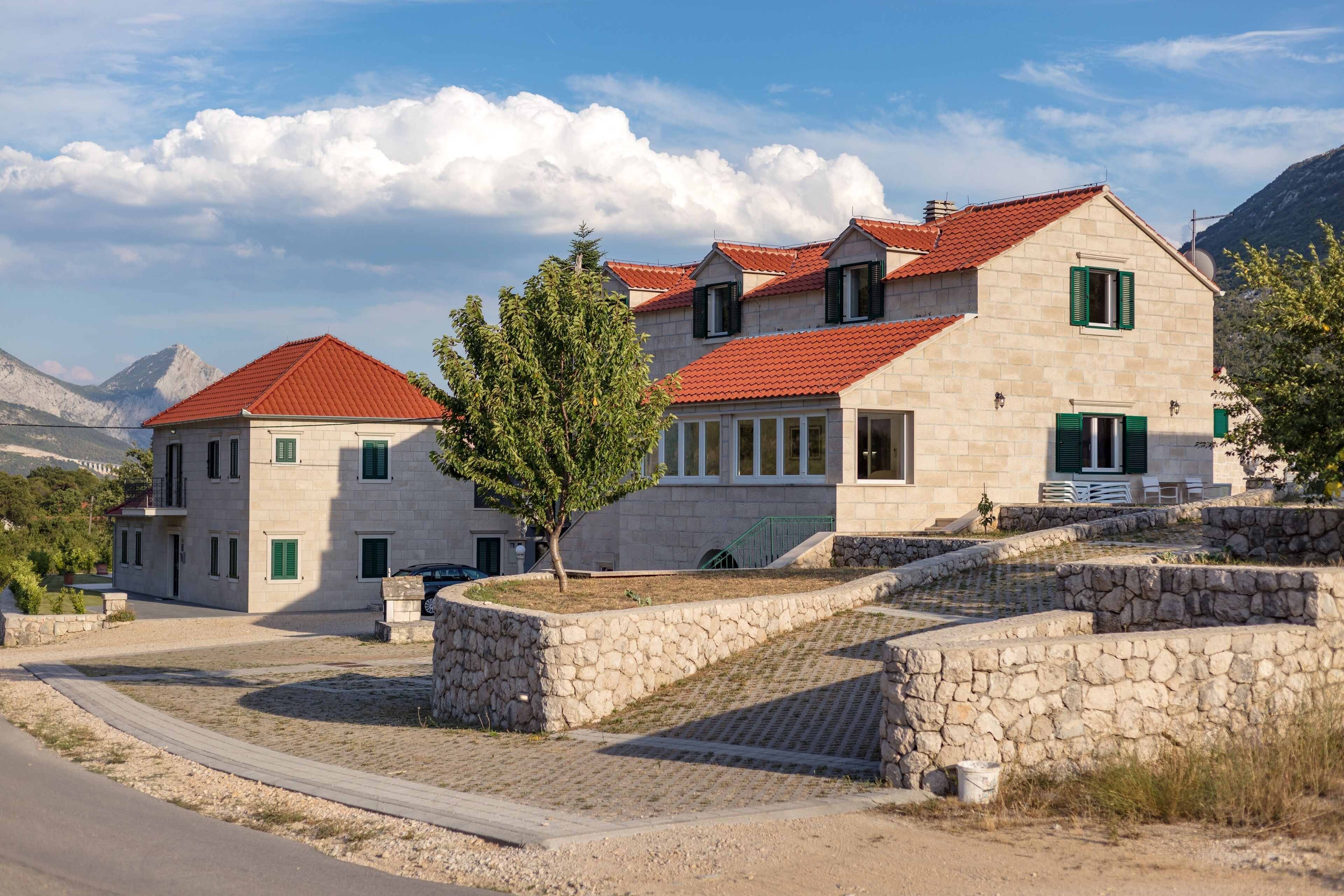 A stone building with red-tiled roofs, a stone staircase, and a paved area.