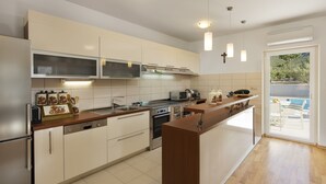 A modern kitchen with a central island, built-in appliances, and pendant lighting. - Villa Roglic (Zagvozd)