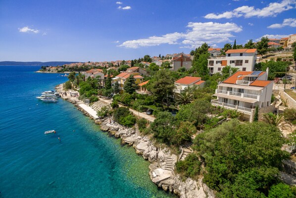 Un pueblo costero con edificios a lo largo del malecón, mar azul cristalino y costa rocosa.
