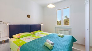 A bedroom with a bed, a nightstand, a window, and a radiator. - Holiday home Duje (Okrug)