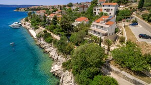 A coastal town with buildings along the waterfront, clear blue sea, and rocky terrain. - Holiday home Duje (Okrug)