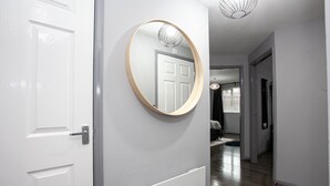 A hallway with a white door, a round mirror, and a radiator. - Trafford Place (Manchester)
