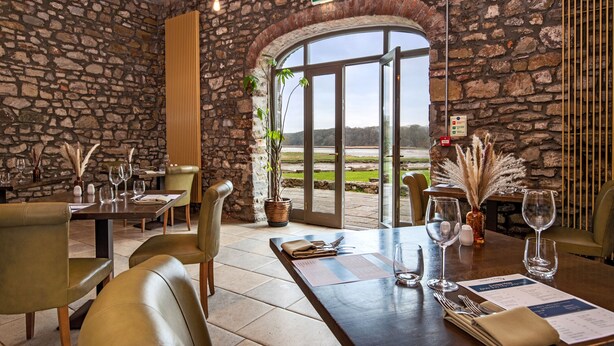 Un restaurant aux murs de pierre, doté d’une grande porte en arc et offrant une vue sur l’extérieur.