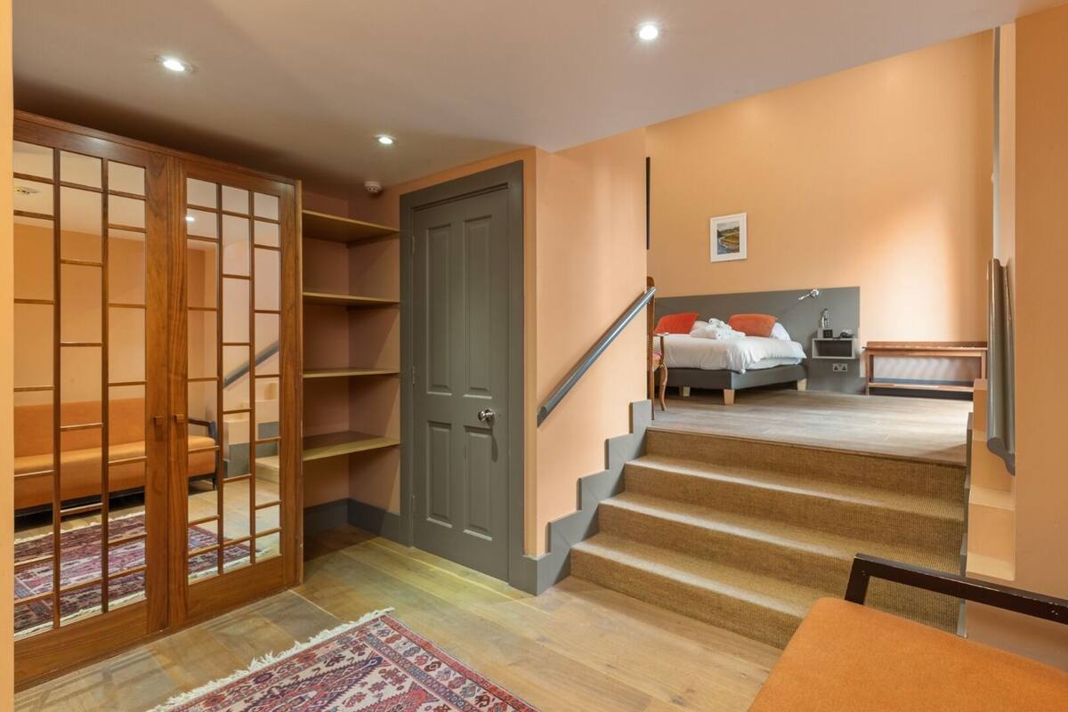 Een trap die leidt naar een slaapkamer met een bed, nachtkastje en stoel.