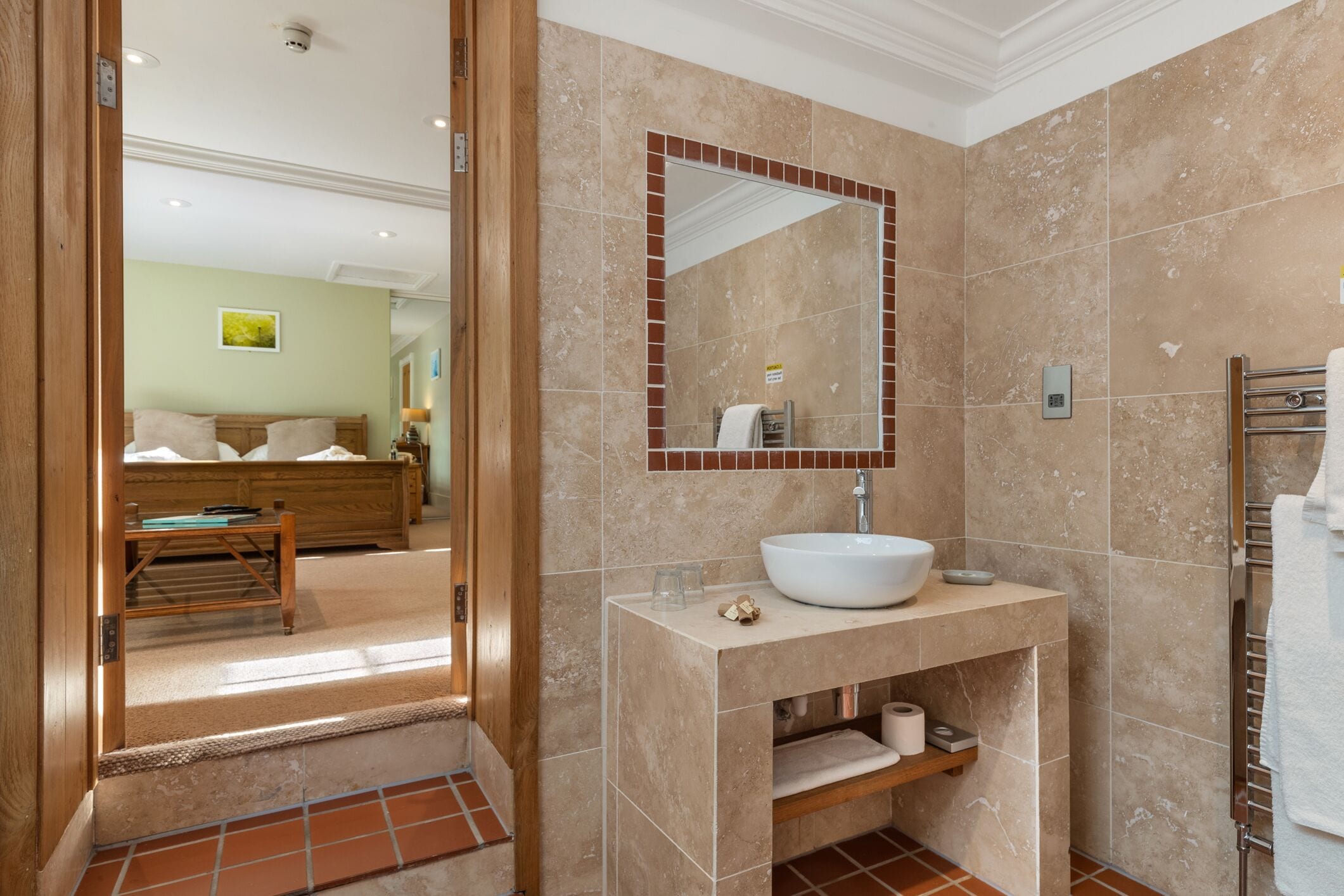 A bathroom with a large mirror, a sink, and a towel rack.
