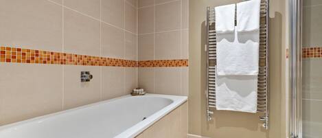 A bathroom with a bathtub, a shower, and a towel rack.