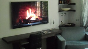 Una sala de estar moderna con televisor de pantalla plana, chimenea, comedor y aire acondicionado integrado.