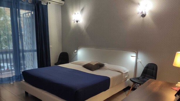 Una habitación de hotel con cama, escritorio y dos sillas.