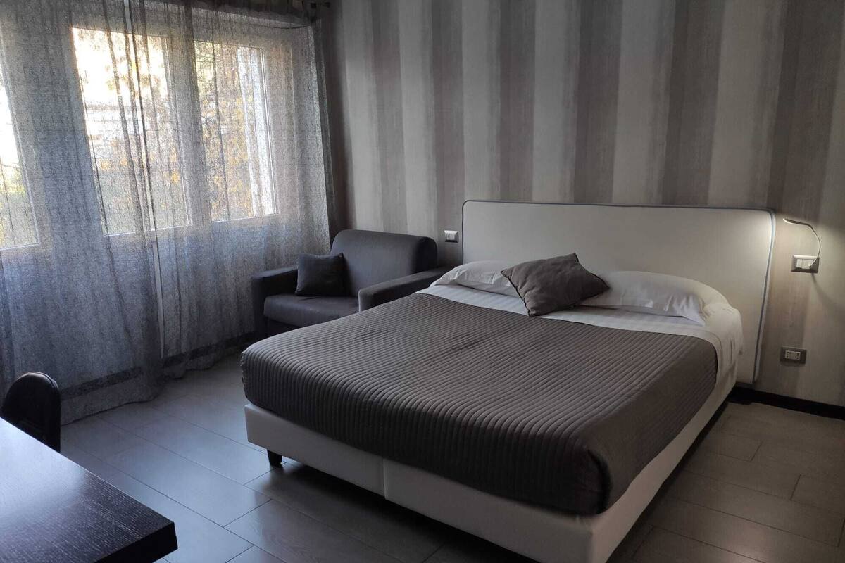 A modern hotel room with a large bed, a desk, and a chair.