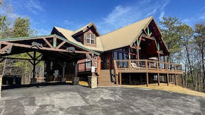 A lodge with a covered porch, a second-story balcony, and a stone foundation.