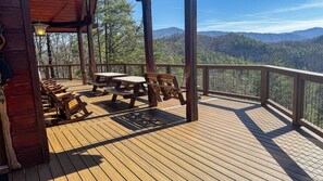 A wooden deck with picnic tables and benches, overlooking a forested mountain range. - Brookstone Lodge - 6 Bedroom -Dog Friendly-Pool Access-Theater-Game Room-Hot Tub (Sevierville)