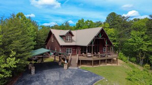 A rustic lodge with a wooden exterior, a covered deck, and a stone staircase leading to the entrance.