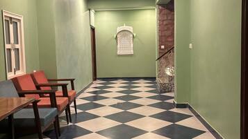 A hallway with a checkered floor, green walls, and a staircase with a decorative railing.