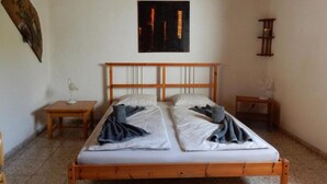 A simple, clean room with a wooden bed, two bedside tables, a wall clock, and a framed picture. - Palmera, quiet studio with terrace and view to the mountains (Las Zocas)