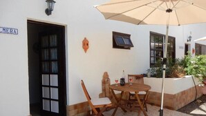 A patio area with a wooden table and chairs, a beige umbrella, and a door labeled "MERA". - Palmera, quiet studio with terrace and view to the mountains (Las Zocas)