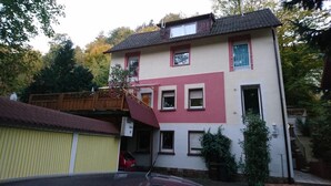 Un bâtiment à deux étages, doté d’une façade rouge et blanche, d’un garage visible et d’un escalier menant à l’étage supérieur.