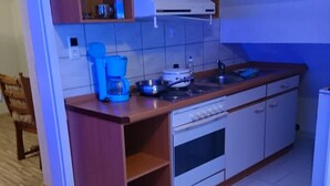 Une cuisine compacte avec des meubles de rangement en bois, un four encastré et une machine à café.