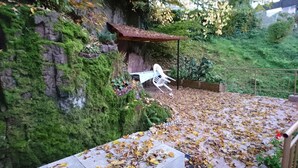 Un espace jardin agrémenté d’une chaise blanche, d’une petite structure en bois et d’un mur de pierre recouvert de verdure.