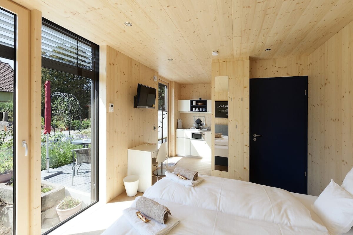 Quarto moderno em madeira, com cama, escrivaninha e televisão.