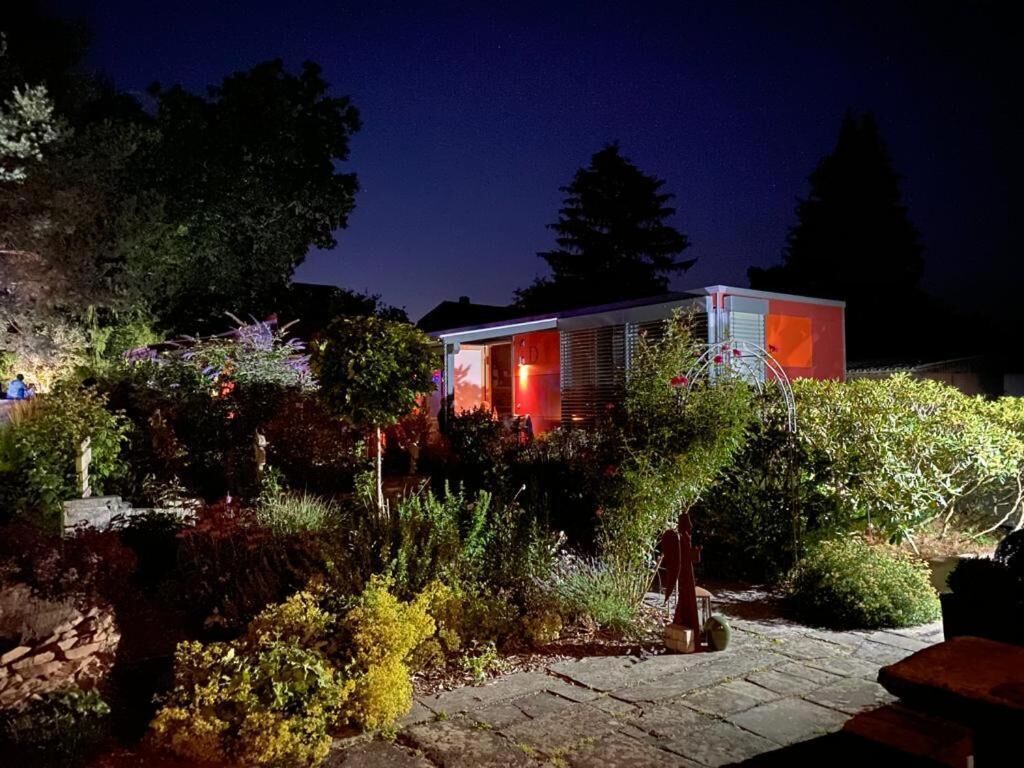 A modern building with a glass facade, surrounded by a landscaped garden with various plants and a stone pathway.