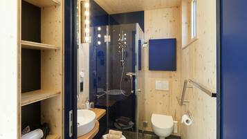 Un baño moderno y compacto con ducha envuelta en vidrio, un lavabo e inodoro.