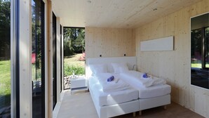 Un dormitorio moderno con una cama grande, paredes de madera y vistas al exterior.