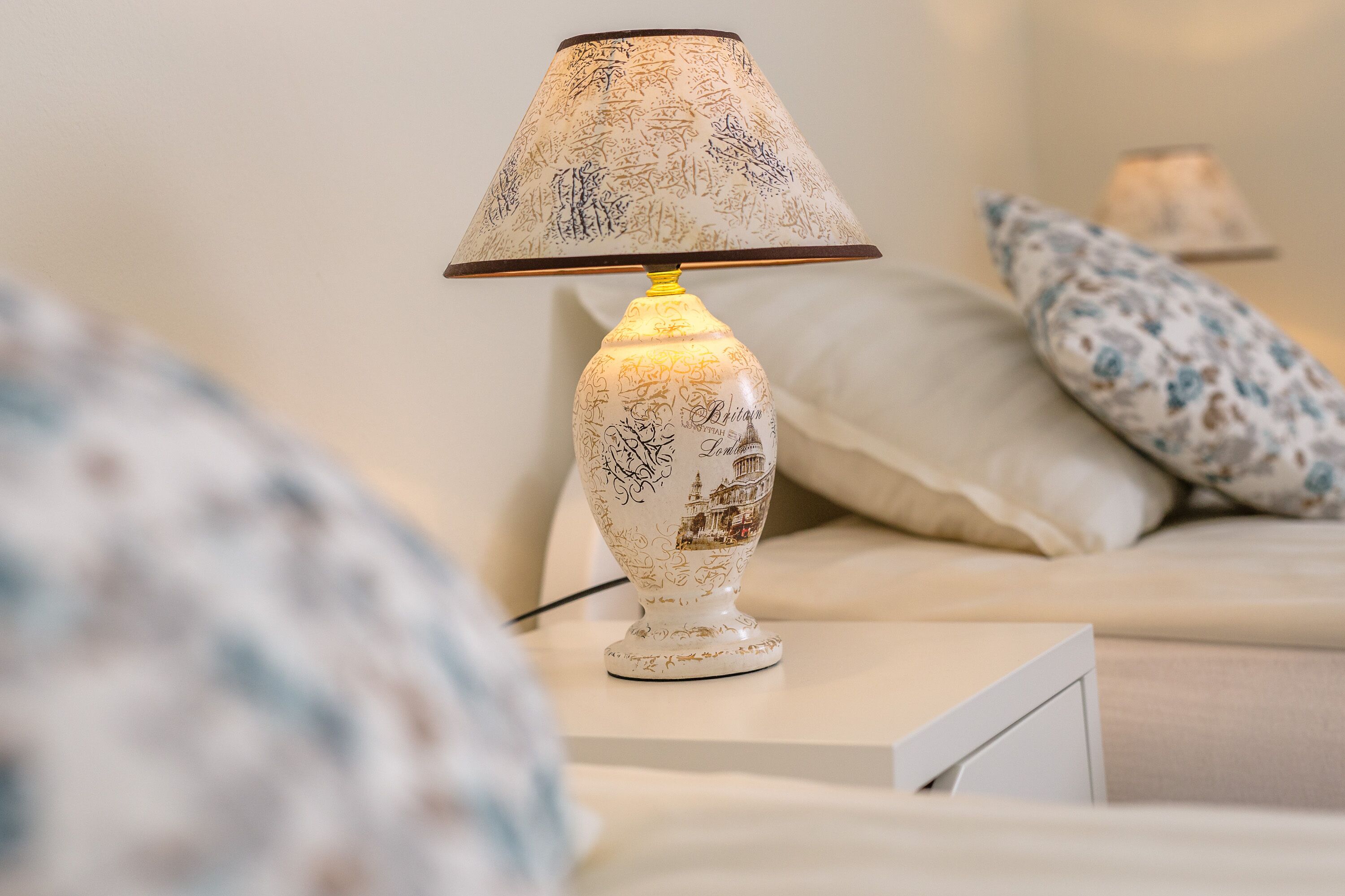 A bedside table with a lamp featuring a decorative design.