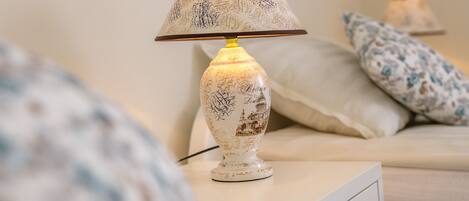 A bedside table with a lamp featuring a decorative design.