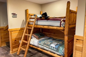 Una cama litera con escalera, cabecera de madera y colcha acolchada.
