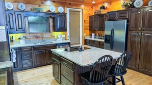 A modern kitchen with dark wood cabinets, granite countertops, and stainless steel appliances. - Paradise Found - Cabin (Sevierville)