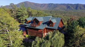 A large log cabin with multiple levels, surrounded by dense forest and mountains. - Papa Bear's Den - Cabin (Sevierville)