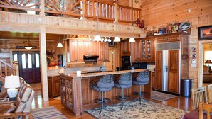 A spacious wooden cabin with a large kitchen, dining area, and a bar with stools. - Papa Bear's Den - Cabin (Sevierville)