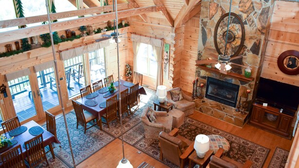 A spacious wooden cabin with a stone fireplace, a dining area, and a cozy living room. - Papa Bear's Den - Cabin (Sevierville)