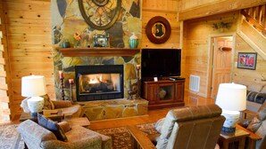 A cozy log cabin interior with a stone fireplace, comfortable seating, and a television. - Papa Bear's Den - Cabin (Sevierville)