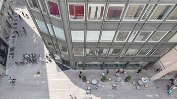 A modern building with a rooftop terrace featuring seating areas, a bike rack, and a view of the surrounding cityscape.
