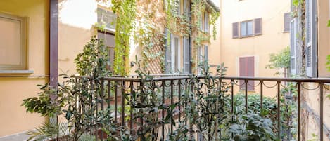 En balkon med plantekasser og gelænder i metal.