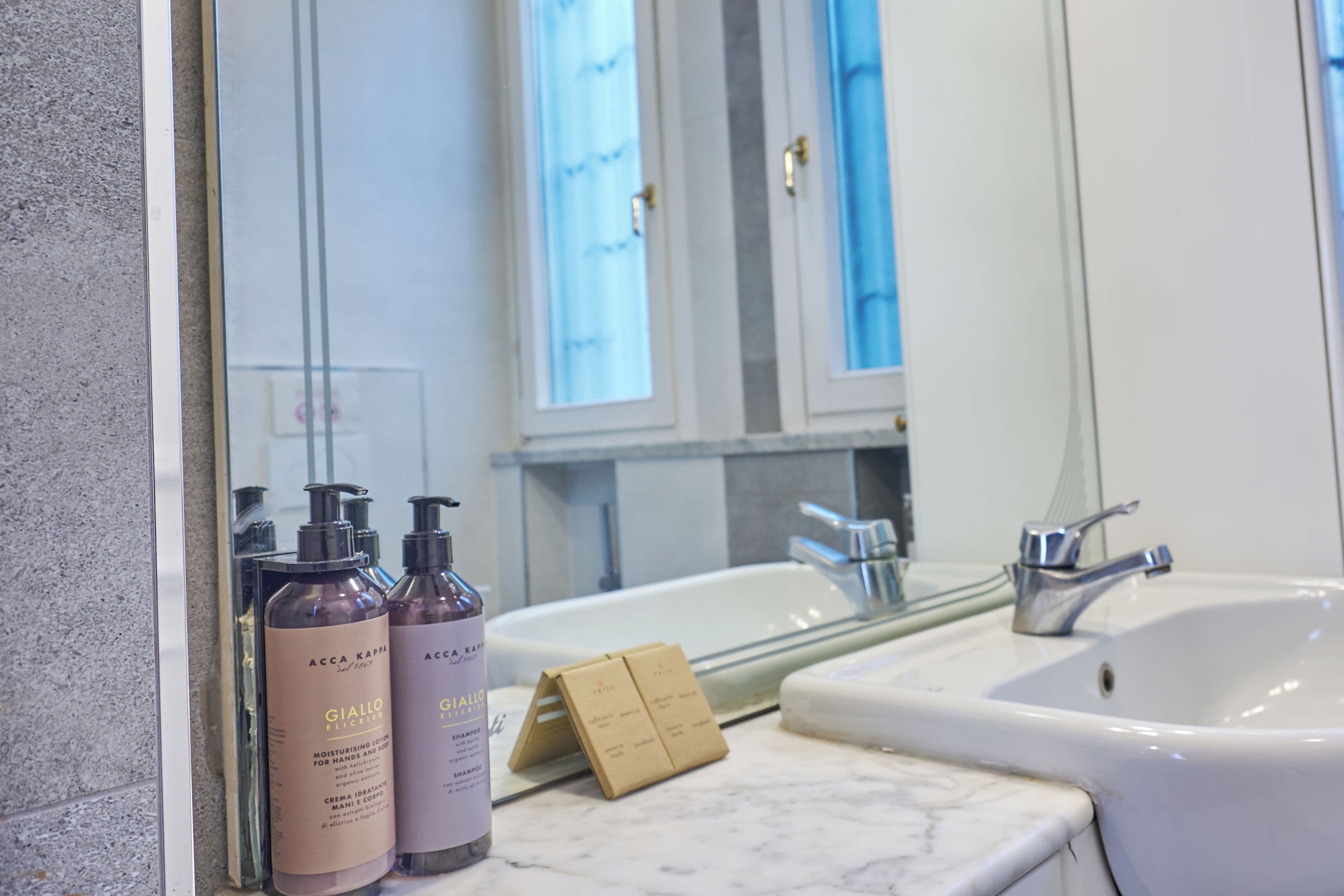 A bathroom with a white sink, a mirror, and two bottles of Giallo shampoo.